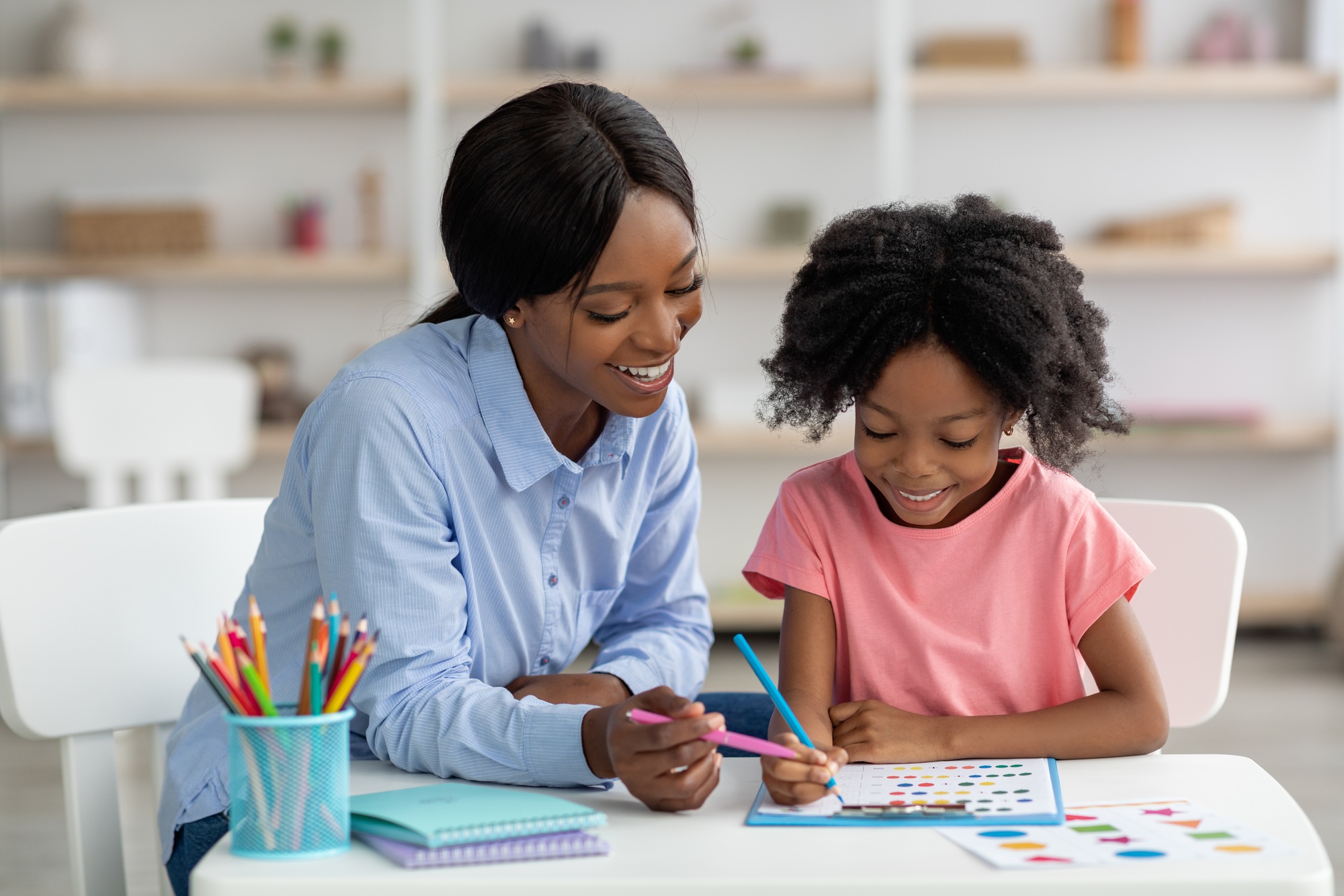 Cute little black girl exercising with teacher at daycare